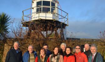 Group image of people standing in front of Lighthouse structure