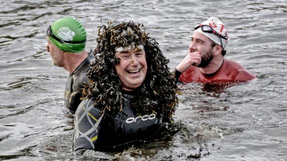 image of 3 swimmers.  One laughing with seaweed on his head